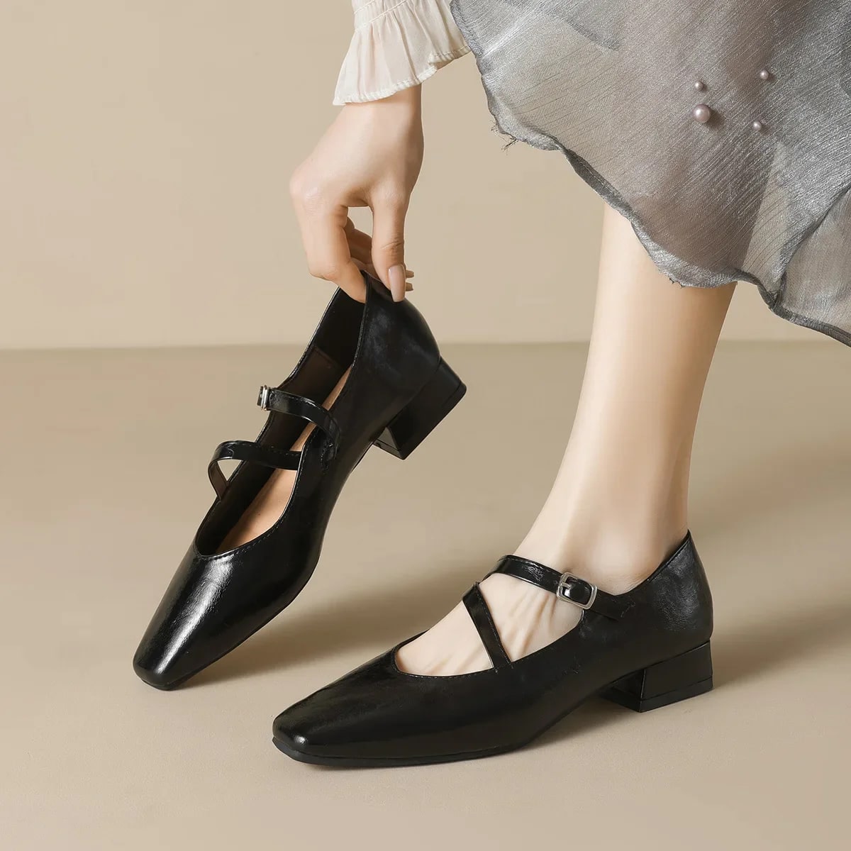 Giày đen đế vuông đang được xỏ vào chân phụ nữ trên nền be sáng